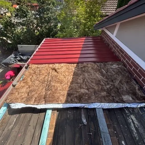 Colorbond metal roof sheets being installed over new insulation — Blue Mountains